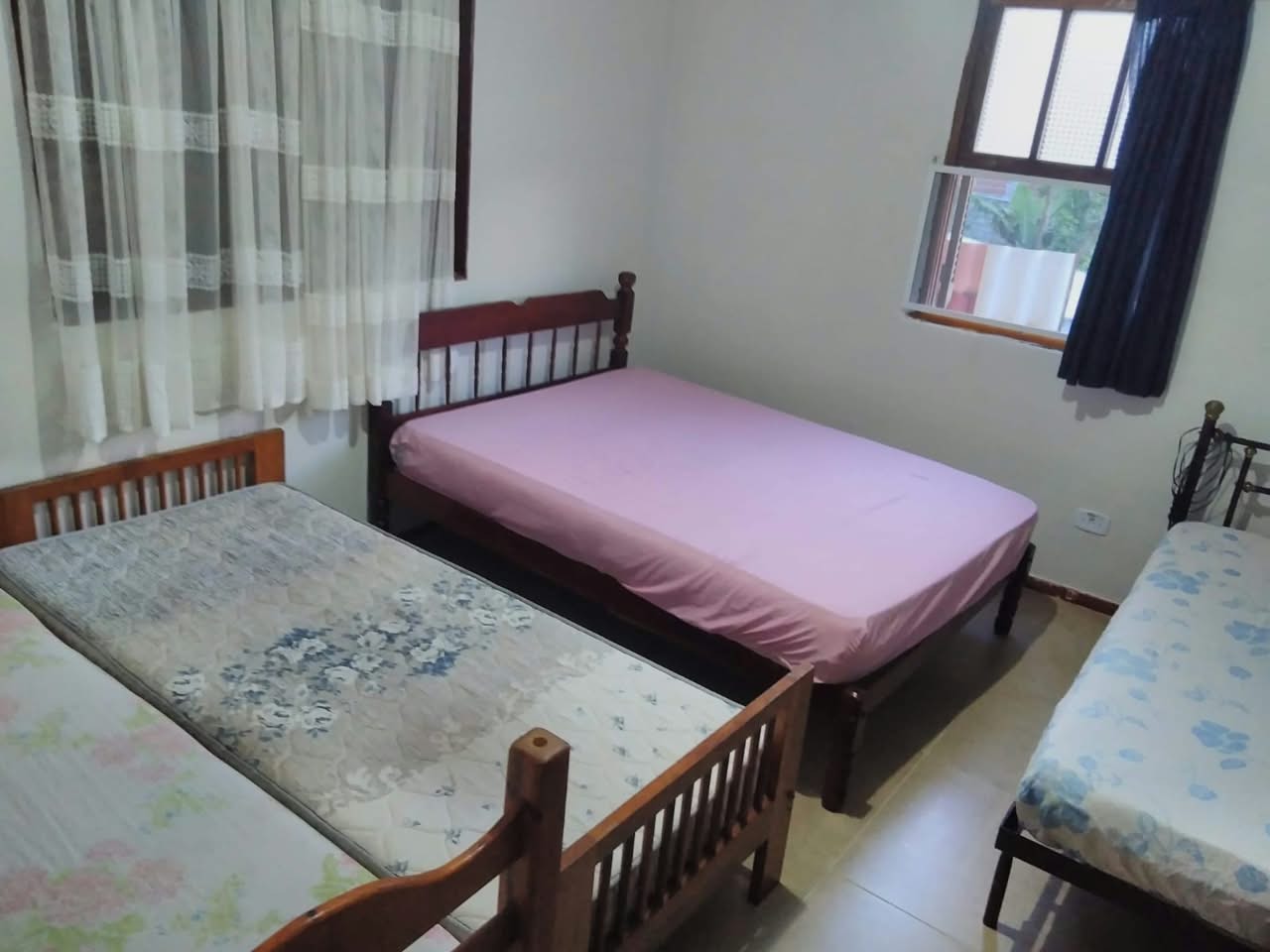 Quarto de hospedagem da chácara com três camas de solteiro, mostrando a capacidade de pernoite oferecida aos hóspedes.