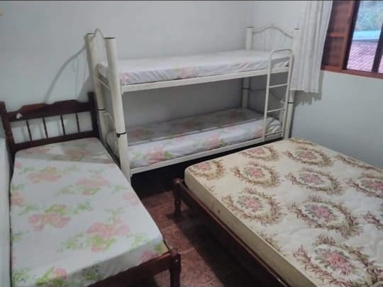 Quarto de hospedagem com beliche e cama de solteiro, mostrando a capacidade de pernoite da chácara